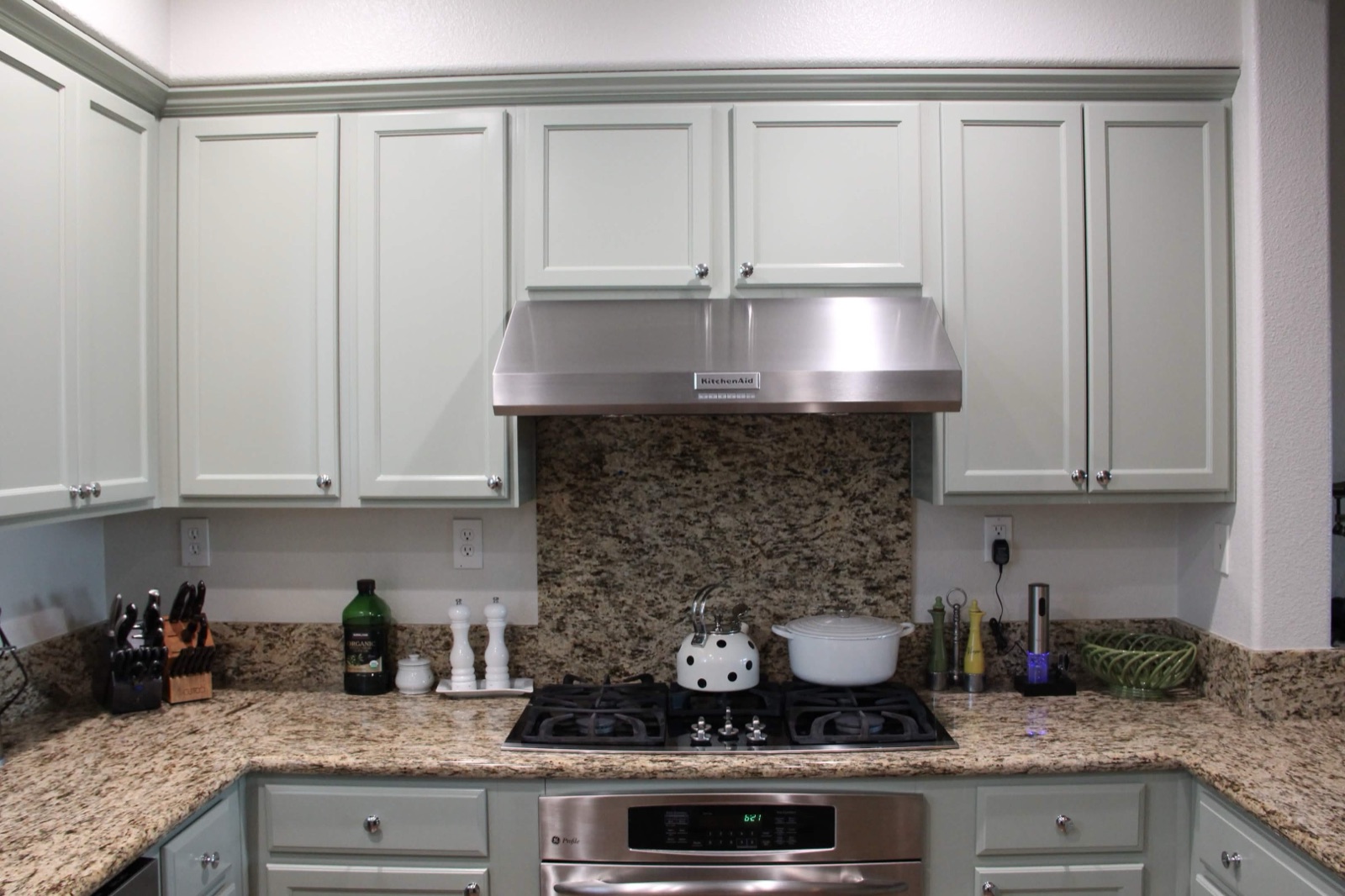 Sage green cabinets around stainless range hood